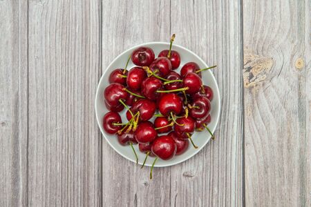 Red ripe juicy sweet cherry lies on vintage wooden background.の写真素材