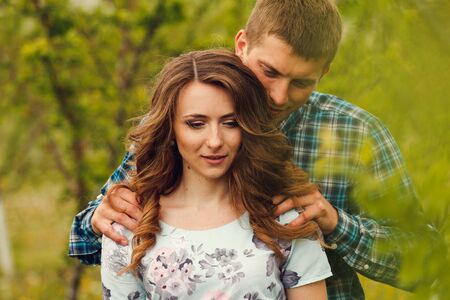 Attractive young happy couple on a spring garden walk in the countryside in front of a tree covered...