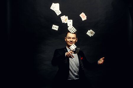 Closeup of man magician with two playing cards in his hand over grey backgroundの写真素材