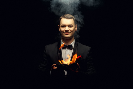 Young brunette magician in costume performing flame tricksの写真素材