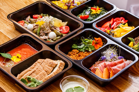 Healthy food and diet concept, restaurant dish delivery. Take away of fitness meal. Weight loss nutrition in foil boxes. Steamed veal with cous and vegetables at woodの写真素材