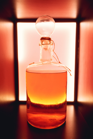 Red rustic bottle of sour liqueur isolated. National drinks. Natural drinks.  Homemade alcohol. Color bottles with homemade alcohol. Old rustic vintage brandy bottle.の写真素材