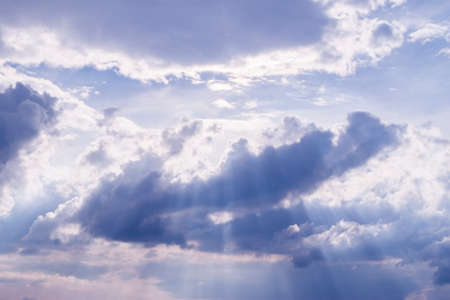 sun rays among blue clouds, can be used as backgroundの写真素材