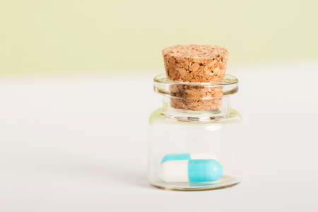 two pills in small glass jar with wooden corkの写真素材