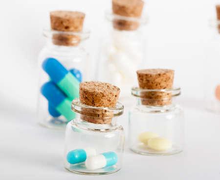 four glass bottles with colorful pills and coksの写真素材