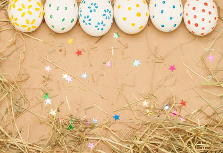 spotted easter eggs on kraft background with hay and starsの写真素材