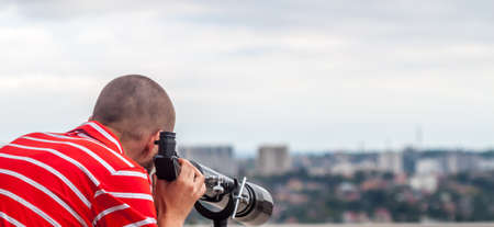 man looking in telescope on the roofの写真素材
