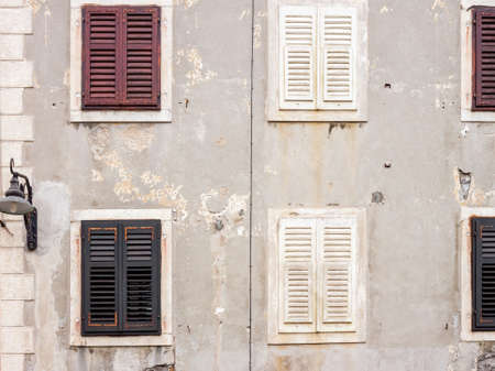 old building wall with shutters and windows as backgroundの写真素材