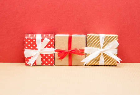 three different christmas presents on red paper background