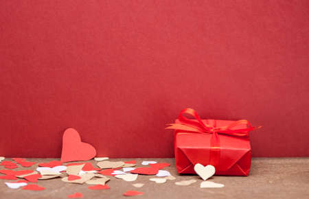 red gift box with bow knot and paper heartsの写真素材