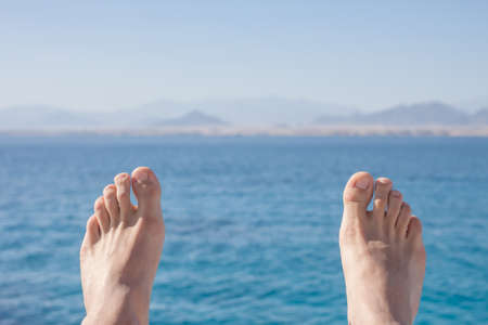 man feet on sea and mountains backgroundの写真素材