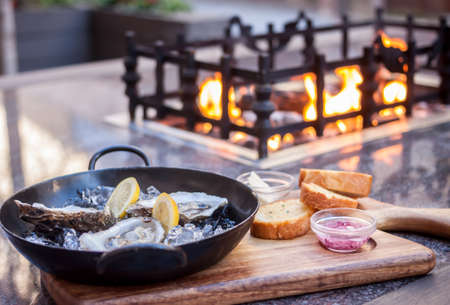 fresh opened oysters fireplace backgroundの写真素材