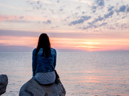 sunset over sea woman looking at horizonの写真素材