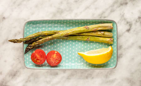 asparagus lemon and tomatoes on small plateの写真素材