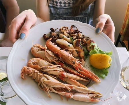 female hands keeping plate with shrimpの写真素材