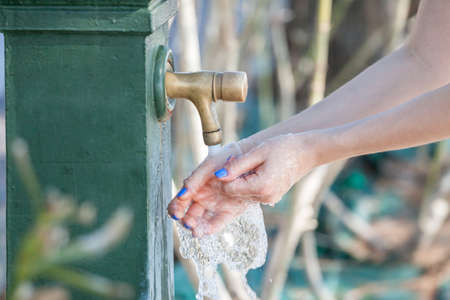 woman washing hands in city fountainの写真素材