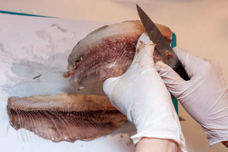 cook cleaning herring fish in the kitchen