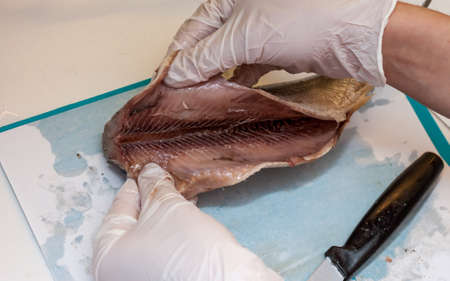 cook cleaning herring fish in the kitchen