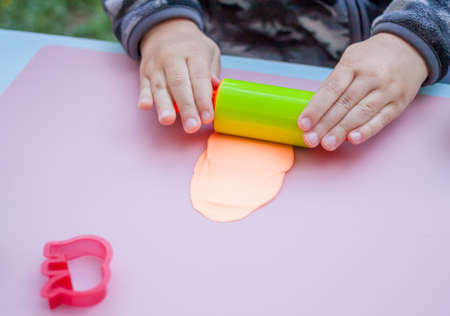 child hands playing with plasticine on blue table top viewの写真素材