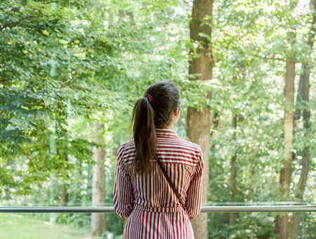 woman looking into the window green forestの写真素材