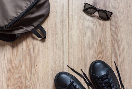 backpack glasses and sneakers on wooden background