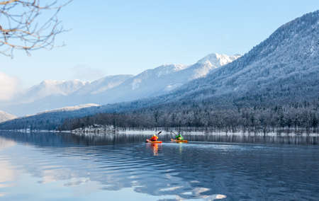 two people kayaking in the winter among mountainsの写真素材