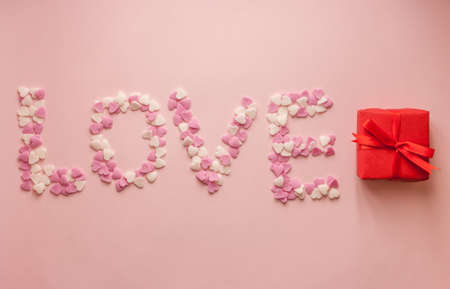 Word love made of small sweet hearts on pink backgroundの写真素材