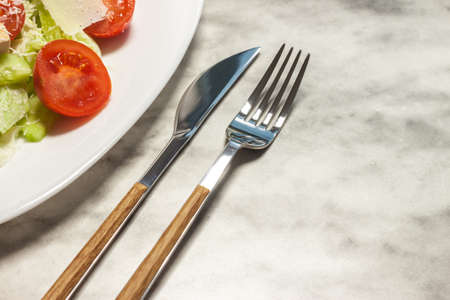 fresh vegetables salad on white plate with stylish cutlery
