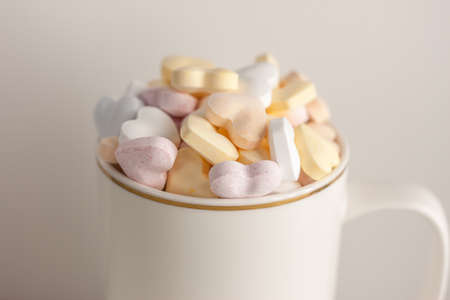 one white cup with heart print full of candy hearts