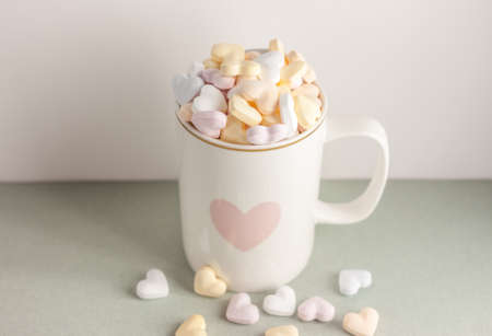 one white cup with heart print full of candy hearts