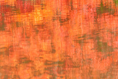 water surface with autumn colors reflection textured backgroundの写真素材