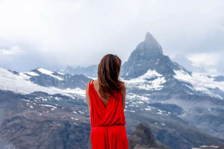 woman in long red dress on background of Matterhorn mountの写真素材
