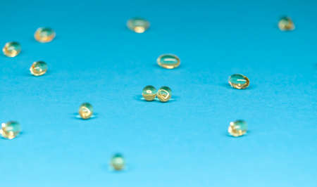 fish oil capsules scattered on blue backgroundの写真素材