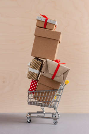 high pyramid of gift boxes in toy shopping cart on wooden backgroundの写真素材