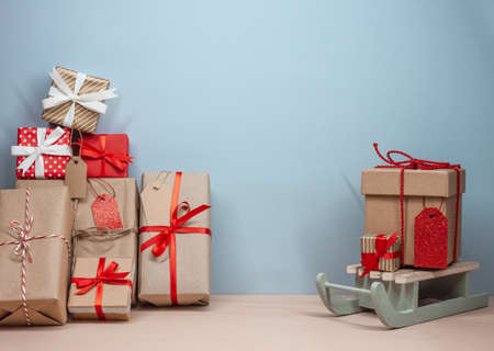 high pile of wrapped christmas gifts and sledges. Blue background. Copy spaceの写真素材