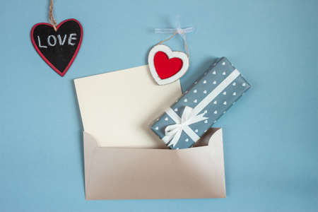 valentines day wooden hearts beautiful envelope and wrapped gift ob blue paper backgroundの写真素材