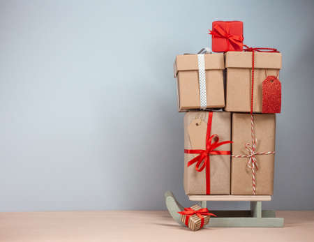 high pile of wrapped christmas gifts on sledges. Blue background. Copy spaceの写真素材