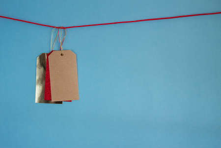 three colorful red yellow golden price tags on rope against blue background. Copy spaceの写真素材