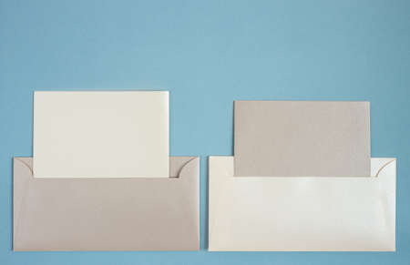 two beige blank open envelopes on blue paper craft background. Copy space. Flat lay.の写真素材