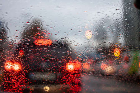 wet windshield with water flows, low visibility, blurred car lights, traffic