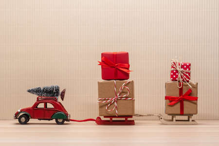 christmas festive decoration red toy car with sledges, wrapped gift and fir-tree