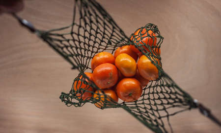 man keeps mandarins in green net bag zero waste conceptの写真素材