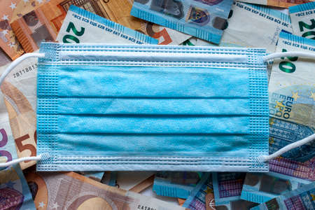 medical blue masks on euro banknotes  background. Concept describing deficit of protection means during virus epidemyの写真素材