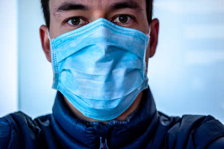young scared man in surgical blue mask taking selfie pictureの写真素材