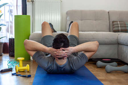 young man exercising doing workout at home in front of laptop