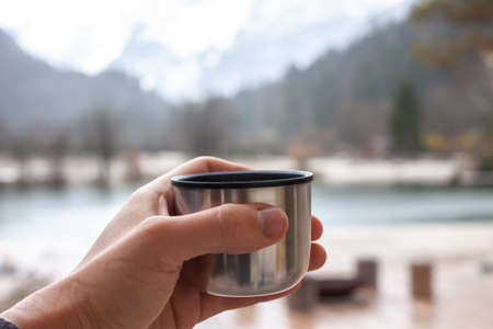 male hand keep  cup walking outdoors mountain background