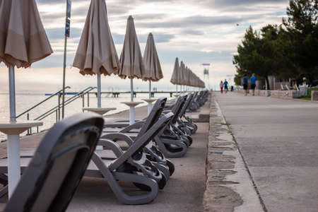 sunset at seaside empty beach with sunbeds and closed umbrellasの写真素材