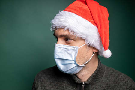 man in red santa claus hat and face mask portraitの写真素材