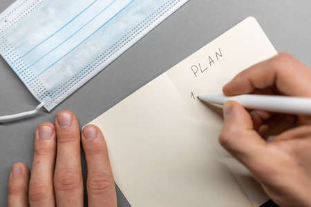 open notebook and face mask hand writing plan