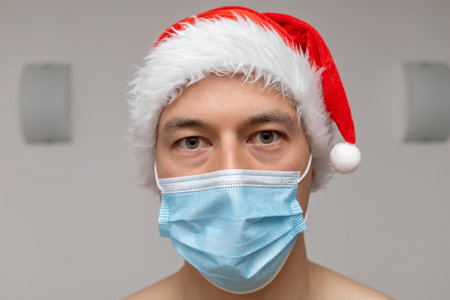 portrait man in Santa Claus hat and face maskの写真素材